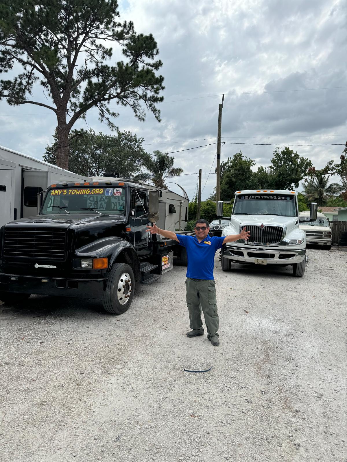 Amy’s Towing team member standing with the company’s tow trucks